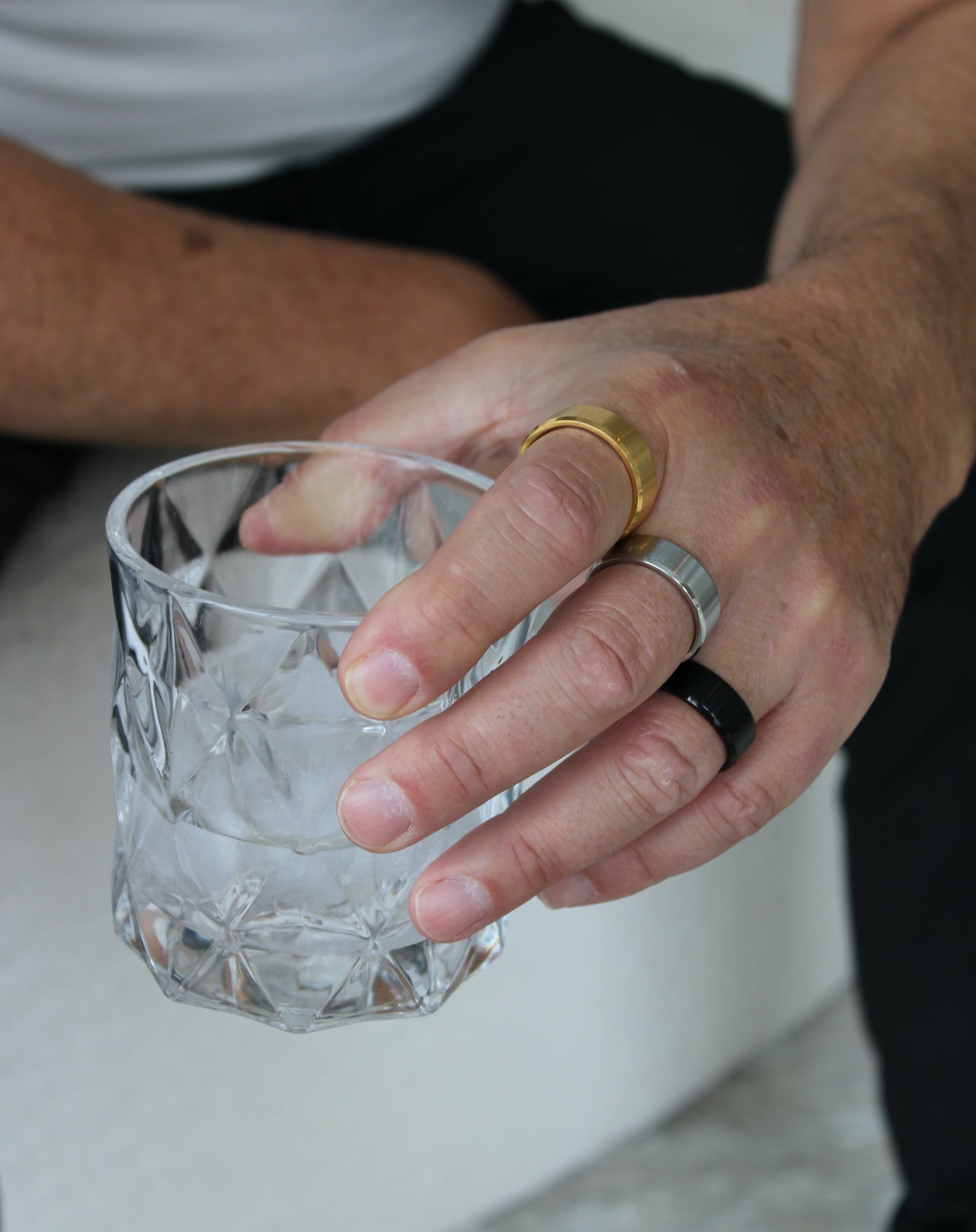 man holding cup with rings on